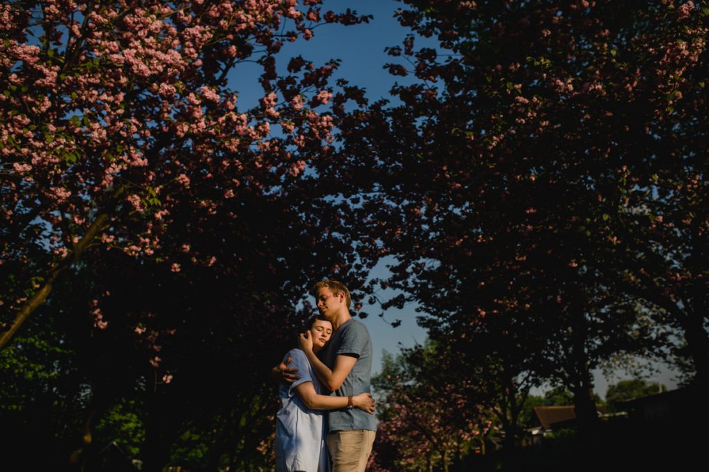 Das Paar beim Paarshooting in Köln vor Bäumen mit Kirschblüten und blauem Himmel - Fotografin: Sonja Yasmin Fotografie, Hochzeitsfotografin in Köln, Bonn und ganz NRW, Fotografin für Portraitfotos und Familienfotos