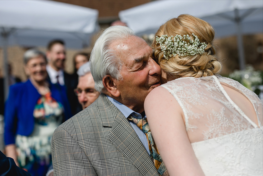 Der Großvater umarmt die Braut und flüstert ihr etwas ins Ohr - Fotografin: Sonja Yasmin Fotografie, Hochzeitsfotografin in Köln, Bonn und ganz NRW, Fotografin für Portraitfotos und Familienfotos
