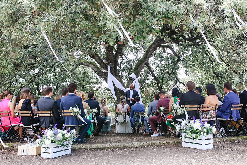 Die freie Trauung mit Gästen und Brautpaar fand unter einem großen geschmückten Baum in der Toskana statt Fotografin: Sonja Yasmin Fotografie, Hochzeitsfotografin in Köln, Bonn und ganz NRW, Fotografin für Portraitfotos und Familienfotos