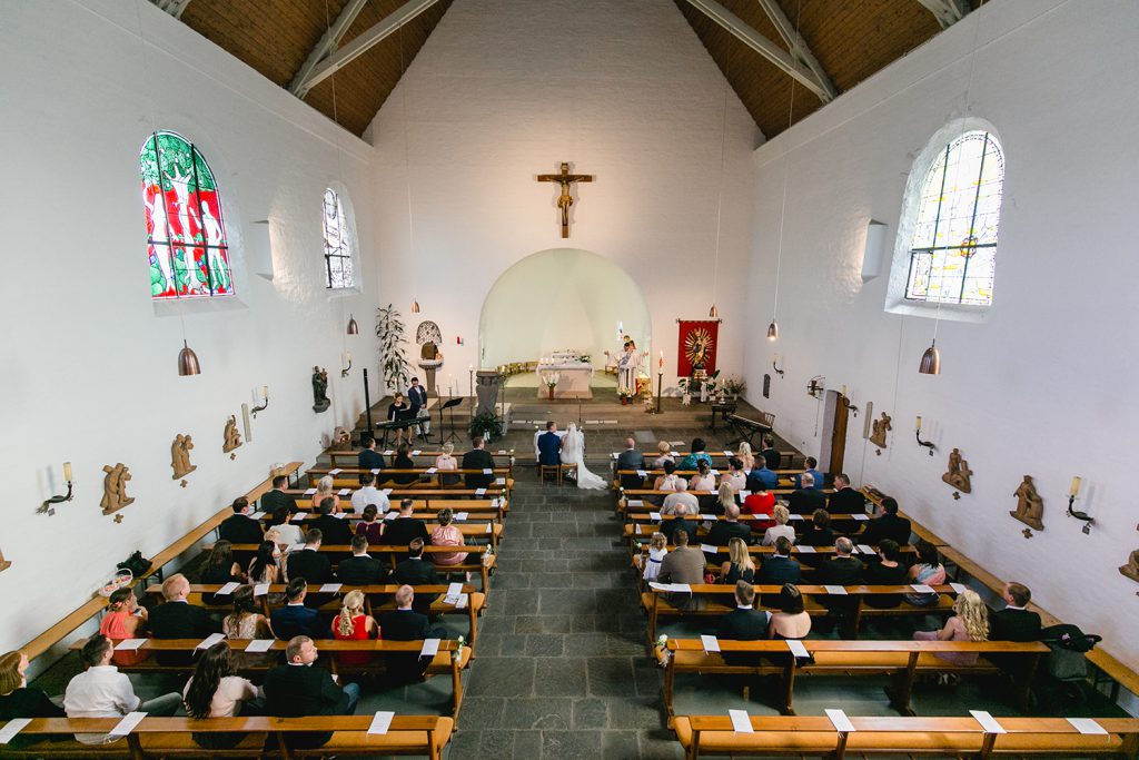 Gesamtaufnahme der Kirche mit Brautpaar während der Trauung - Fotografin: Sonja Yasmin Fotografie, Hochzeitsfotografin in Köln, Bonn und ganz NRW, Fotografin für Portraitfotos und Familienfotos