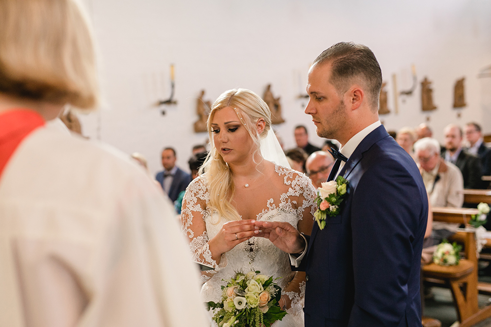 Die Braut steckt dem Bräutigam den Ehering an während der Trauung in der Kirche - Fotografin: Sonja Yasmin Fotografie, Hochzeitsfotografin in Köln, Bonn und ganz NRW, Fotografin für Portraitfotos und Familienfotos