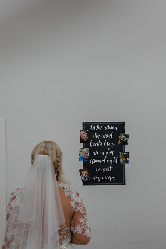 Die Braut betrachtet die Bilder der verstorbenen Angehörigen die nicht an der Hochzeit teilnehmen können - Fotografin: Sonja Yasmin Fotografie, Hochzeitsfotografin in Köln, Bonn und ganz NRW, Fotografin für Portraitfotos und Familienfotos