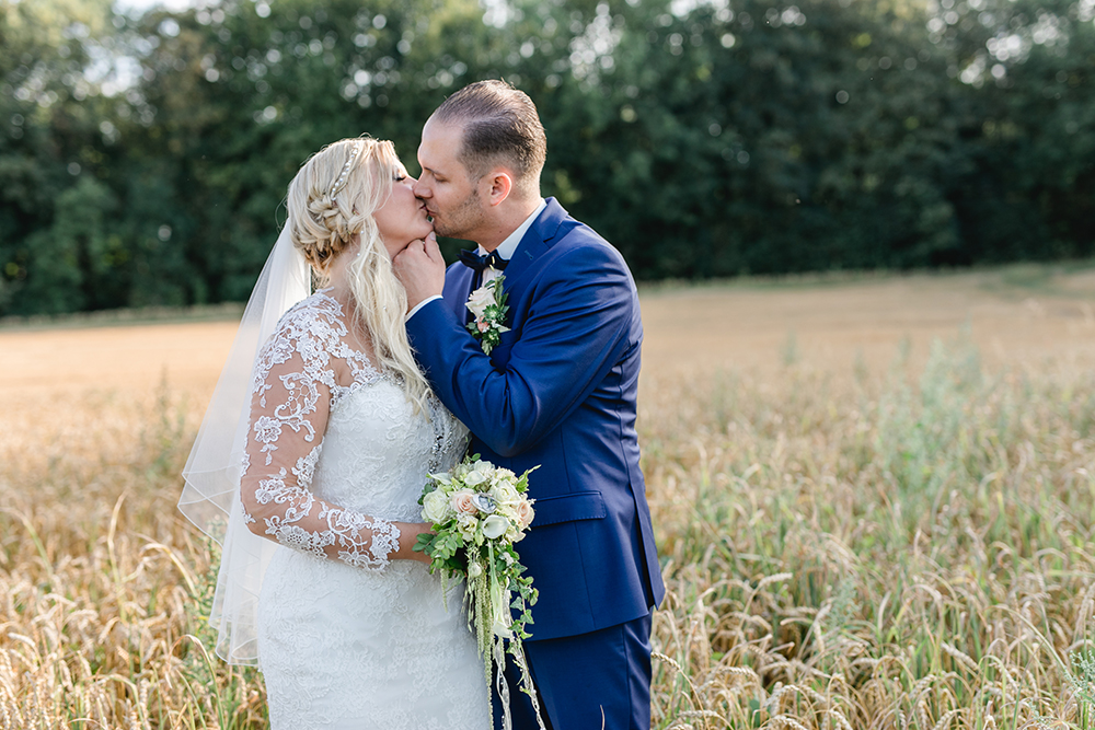 Brautpaar küssend im Feld nach der kirchlichen Trauung - Fotografin: Sonja Yasmin Fotografie, Hochzeitsfotografin in Köln, Bonn und ganz NRW, Fotografin für Portraitfotos und Familienfotos