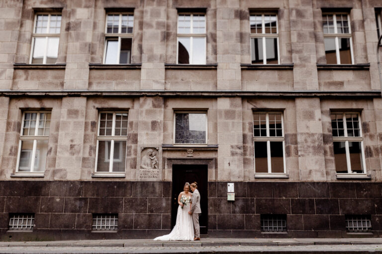 Die beiden stellten sich vor das Gebäude in der Nähe vom Kölner Dom, nachdem sie sich im Standesamt das Ja Wort gegeben haben - Fotografin: Sonja Yasmin Fotografie, Hochzeitsfotografin in Köln, Bonn und ganz NRW"
